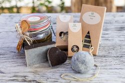 Naturkosmetik mit Moor: Seifen, Körperbutter, Badeschokolade und Badezubehör auf einem Holztisch.