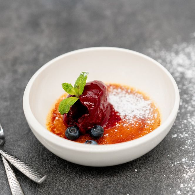 Das Dessert Creme Brulee mit Waldbeeren Eis vom Alten Sägewerk beim s'Ammertal kocht. 
