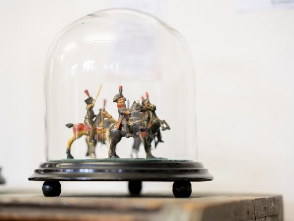 Es werden 3 geschnitze Holzfigurenreiter in einer Glasvitrine gezeigt.