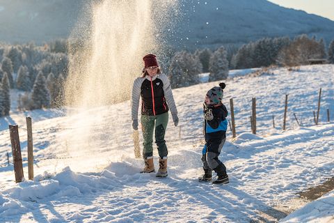 Mama und Kind spielen im Schnee: Familien Spaß beim Winterwandern in den Ammergauer Alpen