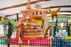 Bunte Indoor-Spielhalle mit großer Piratenschiff-Hüpfburg, Klettergerüst und Spielgeräten im Hoppolino Kinderland Weilheim.