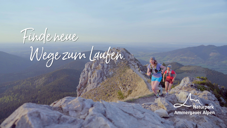 Zwei Trailrunner auf einem felsigen Berggrat mit Blick über die Ammergauer Alpen; darüber steht „Finde neue Wege zum Laufen.“