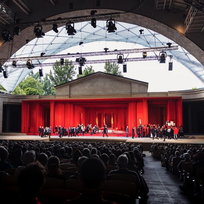 Die Freiluft-Passionsbühne in Oberammergau mit roter Kulisse und zahlreichen Darstellern